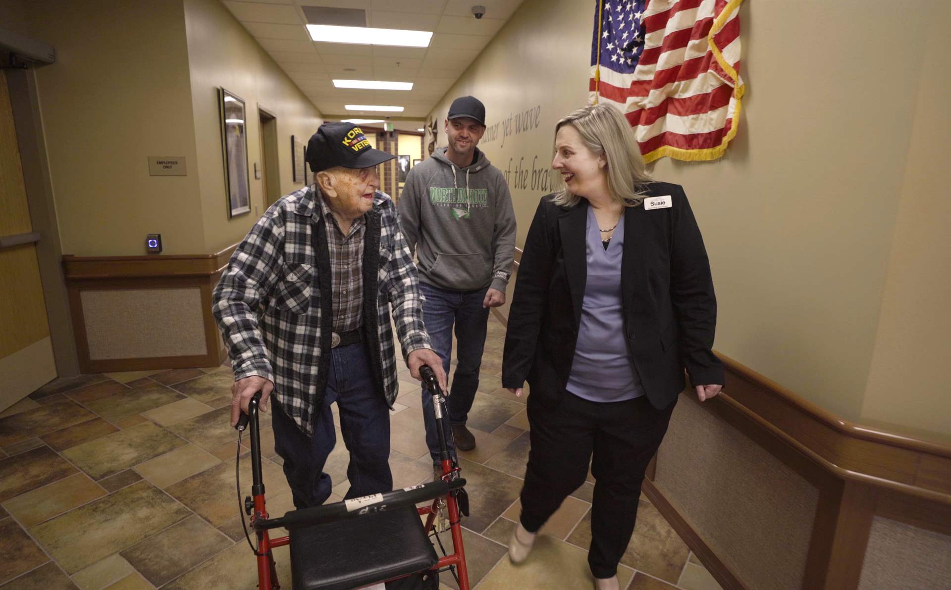 A resident, his family, and staff talking while walking down the hallway.